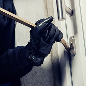 burglar using crowbar to break a home door at night