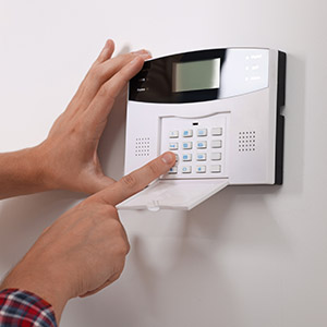 Man entering code on security alarm system at home, closeup